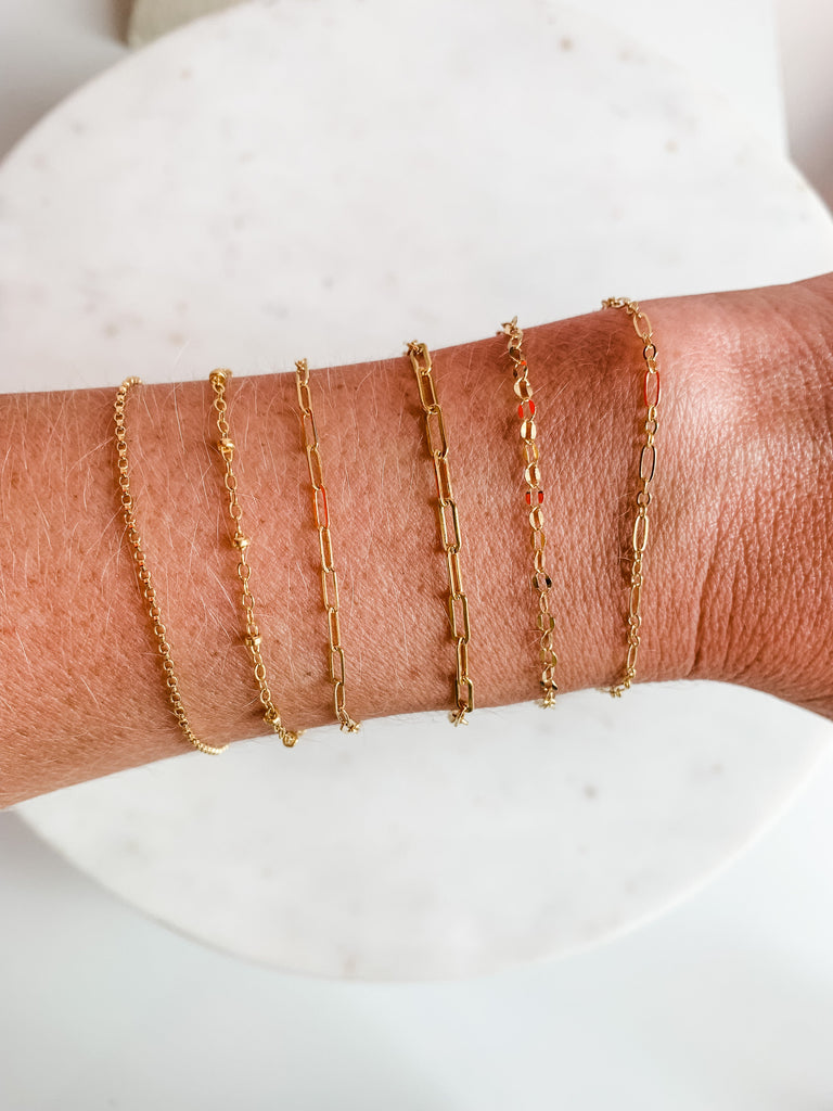 chains are draped across a wrist to show an example of a bracelet
